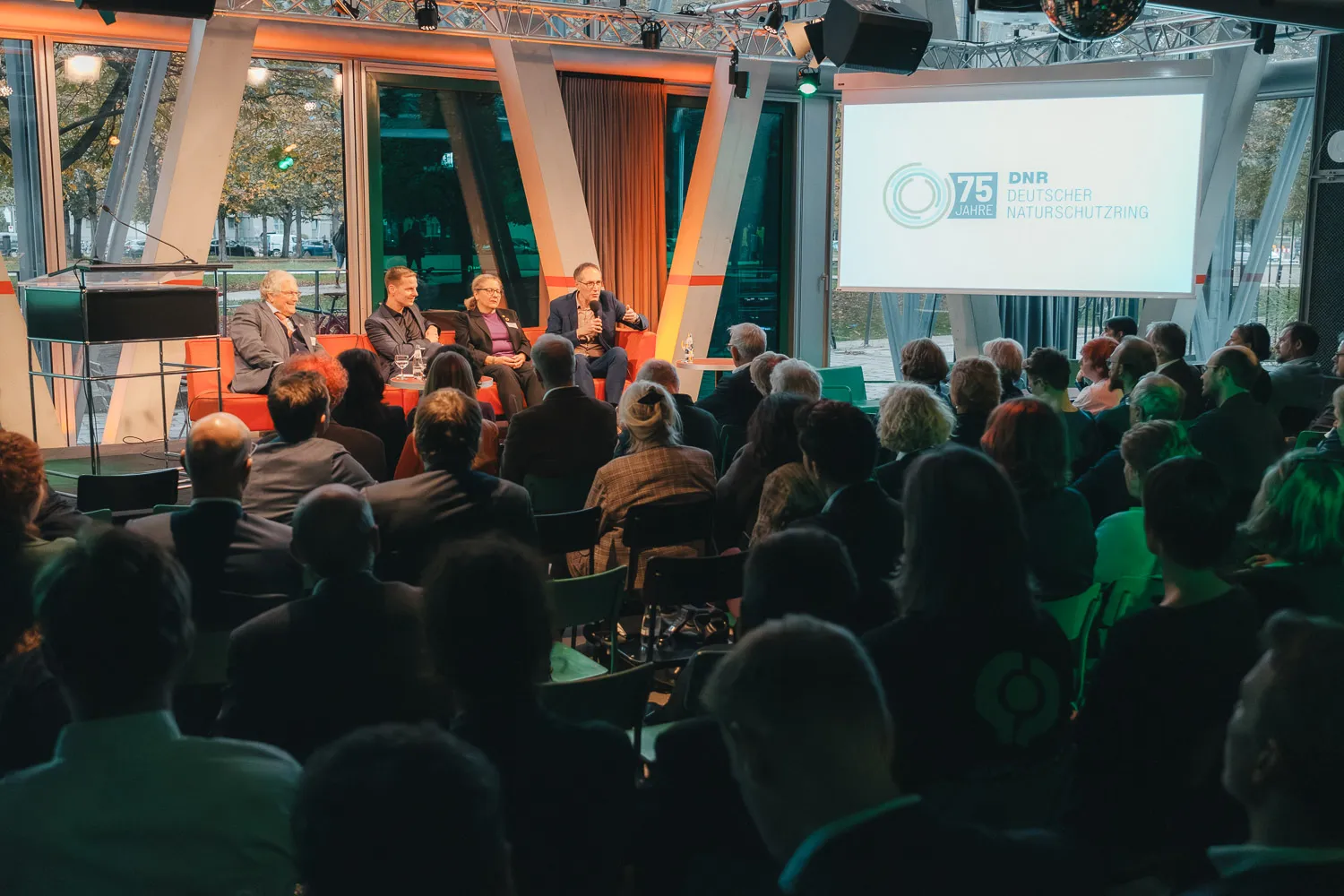 Blick auf den gesamten Saal, der gut gefüllt ist, während vorne auf dem Podium weiterdebattiert wird